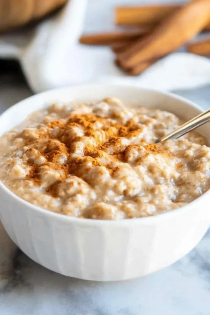 "Eine Schale mit Kürbis-Haferbrei, bestreut mit Zimt, auf einem marmorierten Tisch."