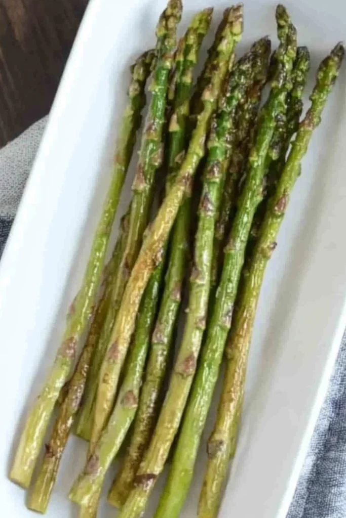 Knusprig gebratener grüner Spargel aus der Heißluftfritteuse, angerichtet auf einem weißen rechteckigen Teller.