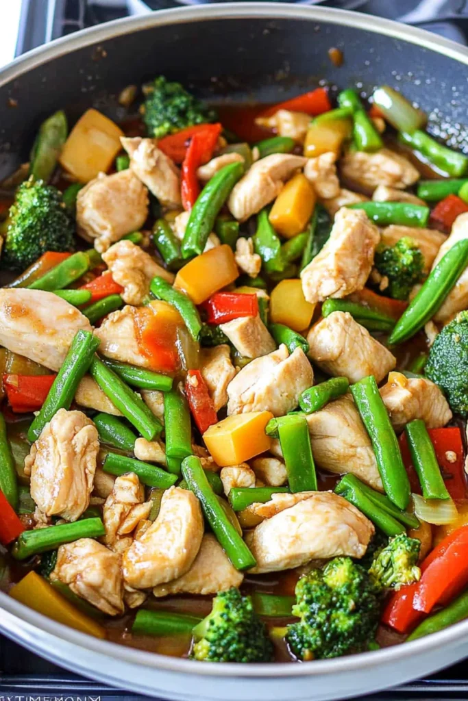 Hähnchenpfanne mit buntem Tiefkühlgemüse wie Brokkoli, Paprika und grünen Bohnen in einer Pfanne.